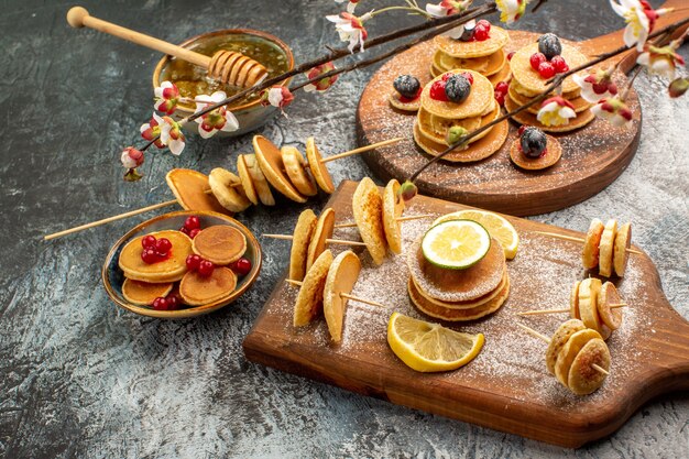 Close-up van benauwde pannenkoeken op snijplank en honing aan de linkerkant van de grijze tafel
