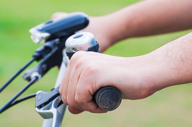 Close-up van de berijdende fiets van de jongenshand. Foto is gericht op dichtstbijzijnde hand.