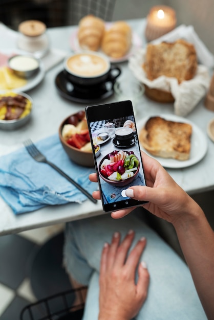 Gratis foto close-up van de hand die foto's van etensbakken maakt