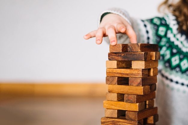 Close-up van de hand die van een meisje houten blokken stapelt