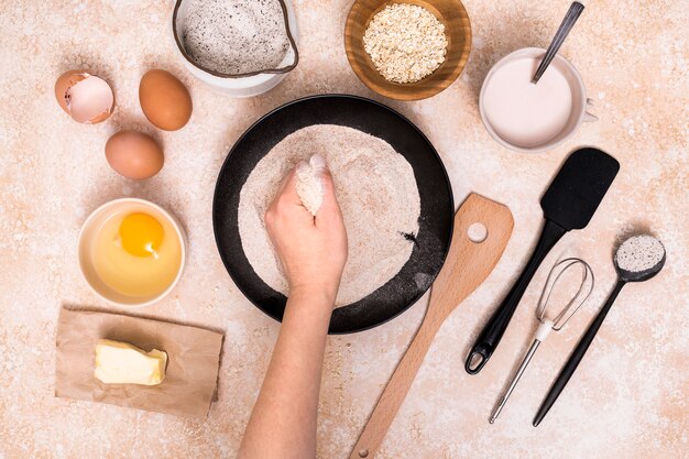 Close-up van de hand met bloem met ingrediënten voor het maken van brood op een gestructureerde achtergrond