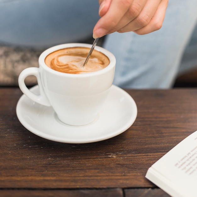 Close-up van de hand roeren lepel in kopje koffie