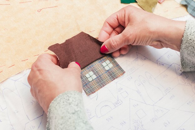 Close-up van de hand stikkende stof van een vrouw binnenshuis vorm op papier