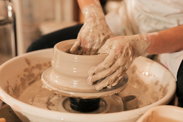 Close-up van de hand van de vrouwelijke pottenbakker met de klei op aardewerk wiel