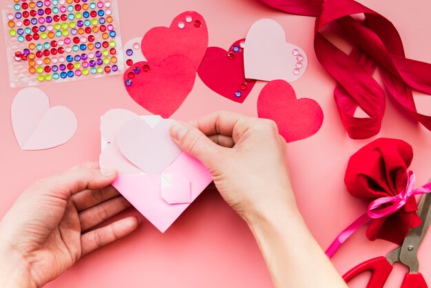 Close-up van de hand van een persoon die het hartdocument binnen de roze envelop plaatst