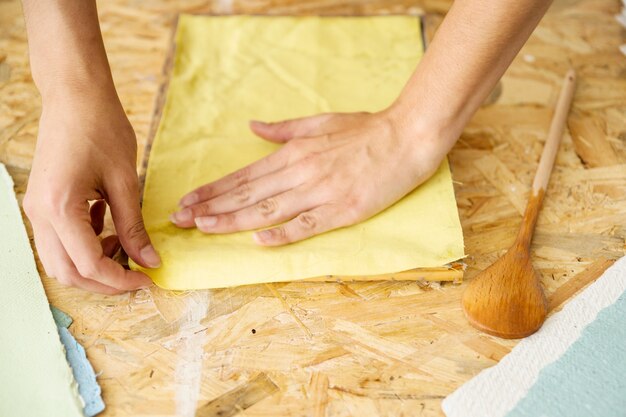 Close-up van de hand van een vrouw die papierpulp bedekt met gele doek