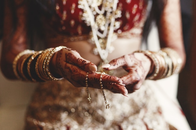 Close-up van de handen van de Indische die bruid met mehndi en het houden wordt behandeld