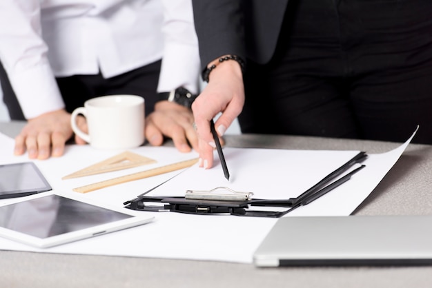 Close-up van de handholding van de onderneemster potlood over het document op klembord over het bureau