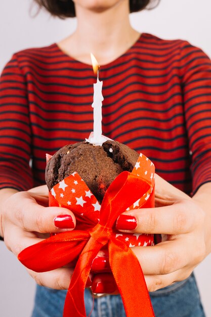 Close-up van de handholding van een vrouw cake met lint en gloeiende kaars