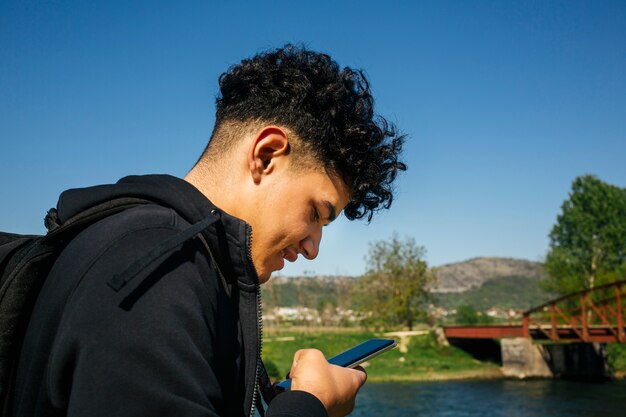 Close-up van de jonge lachende man met behulp van smartphone