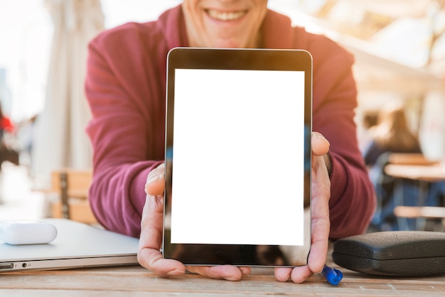 Close-up van de mens die digitale tablet met het lege witte scherm op houten lijst toont