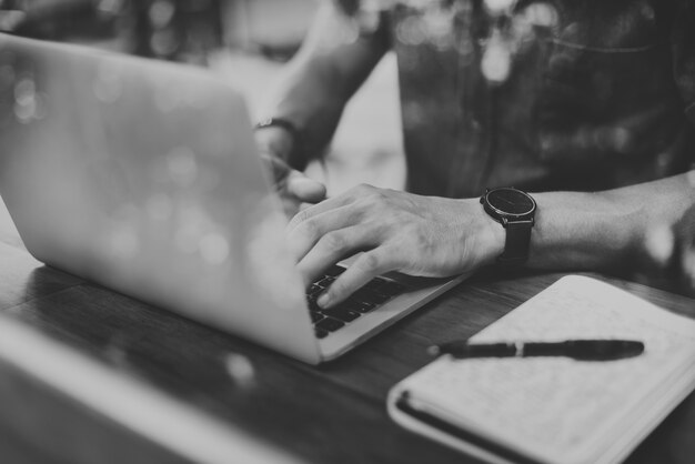 Close-up van de mens die laptop in grayscale koffie met behulp van