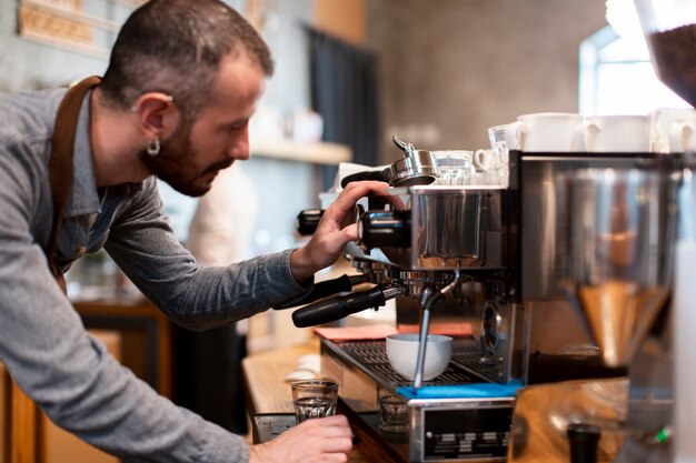 Close-up van de mens die schort draagt die in koffiewinkel werkt