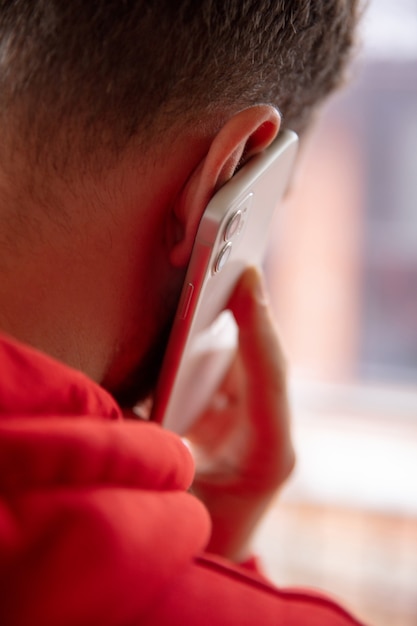 Close-up van de mens met behulp van mobiele slimme telefoon geïsoleerd op een witte muur. Levensstijl, modern technologieënconcept.