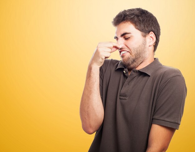 Close-up van de tiener met bruin t-shirt bedrijf zijn neus