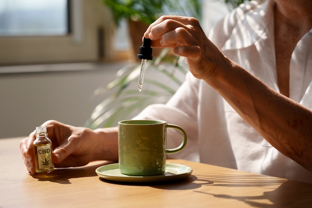 Gratis foto close-up van de vrouw die cbd-olie in een drankje stopt