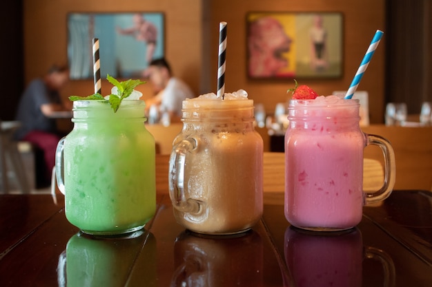 Close-up van drie verschillende smakelijke smakelijke Thaise melkthee op een houten lijst bij een koffie