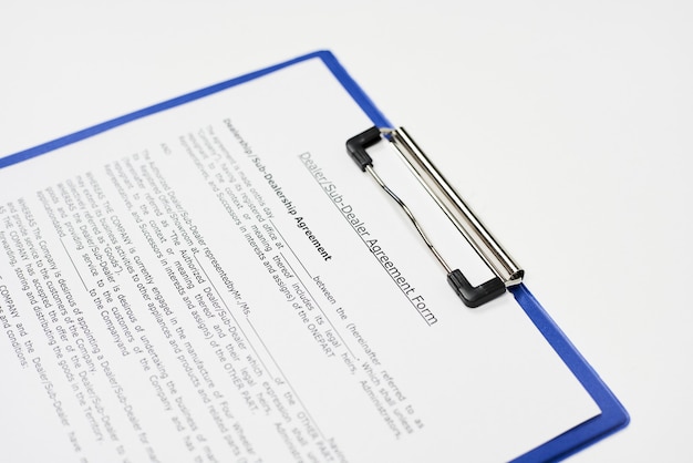 Close-up van een document getiteld "Dealer en sub-dealerovereenkomstformulier" op een blauw klembord