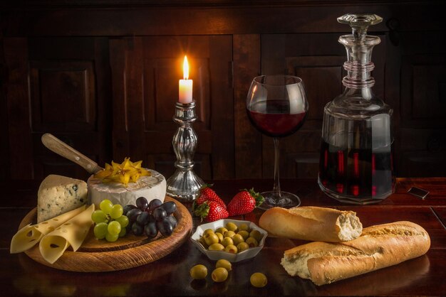 Close-up van een eettafel met een fles wijn, kaas, stokbrood en fruit