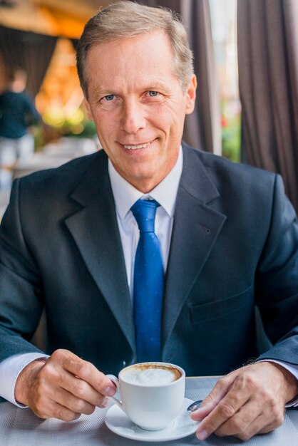 Close-up van een gelukkig volwassen zakenman met een kopje koffie
