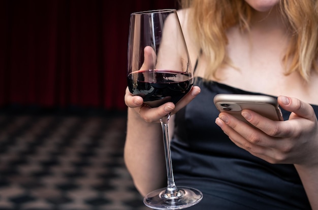 Close-up van een glas wijn in de handen van een vrouw in een avondjurk