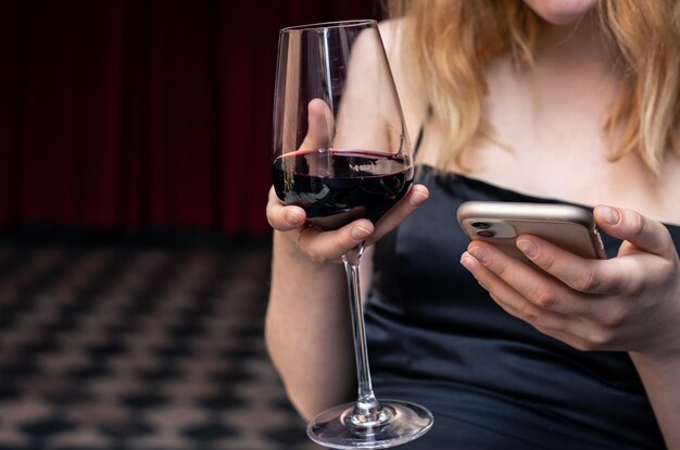 Close-up van een glas wijn in de handen van een vrouw in een avondjurk