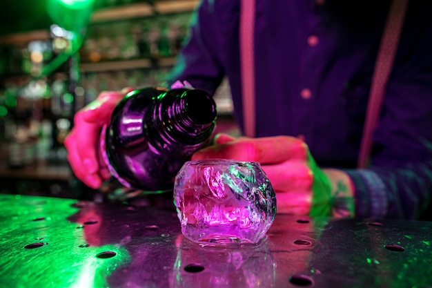 Close-up van een groot smeltend stuk ijs op de toog in vuurvlammen, voorbereiding op een cocktail