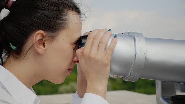 Gratis foto close up van een jonge vrouw die een verrekijker gebruikt voor sightseeing