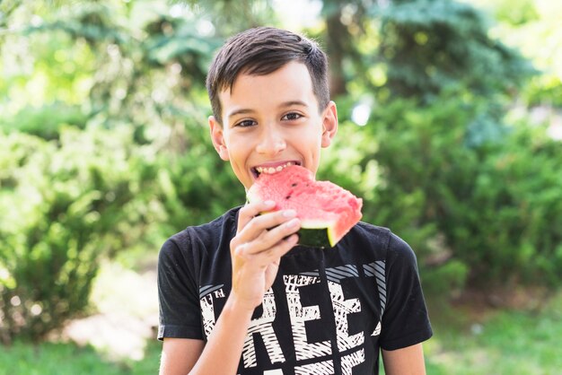 Close-up van een jongen die watermeloenplak in het park eet