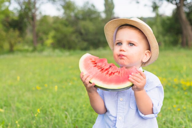 Close-up van een jongen die watermeloenplak in het park eet