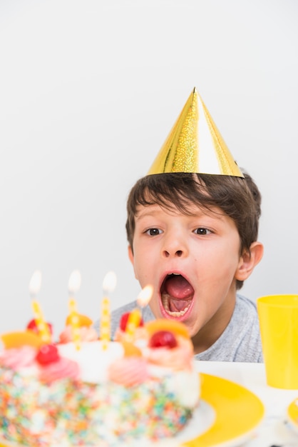 Close-up van een kaars die van de jongens blazende verjaardag feesthoed draagt