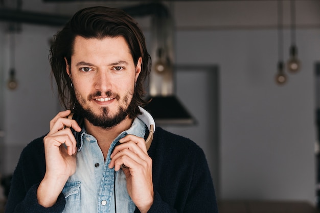 Gratis foto close-up van een lachende jonge man met een hoofdtelefoon rond zijn nek camera kijken