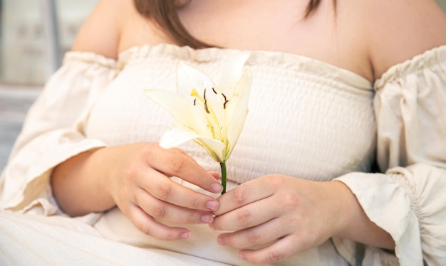 Close-up van een leliebloem in de handen van een vrouw in een linnen jurk