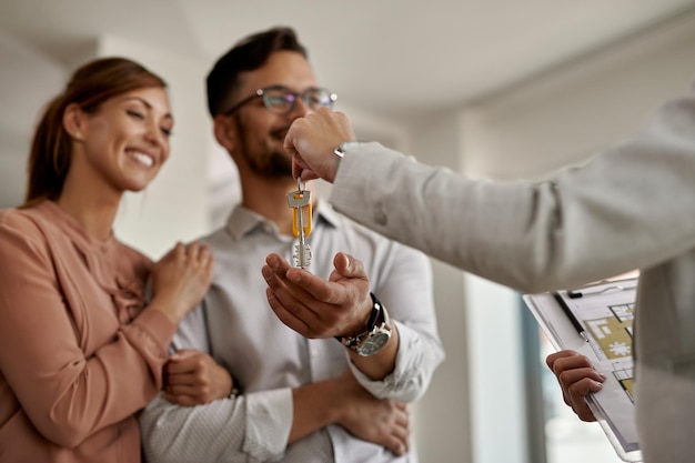 Close-up van een makelaar die aan een paar sleutels van hun nieuwe huis geeft