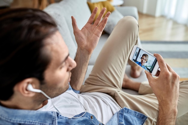 Close-up van een man die een videogesprek voert met een arts via een mobiele telefoon terwijl hij thuis zit