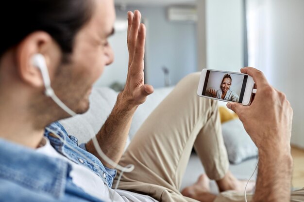 Close-up van een man die mobiele telefoon gebruikt en zwaait terwijl hij videochat met zijn vriendin