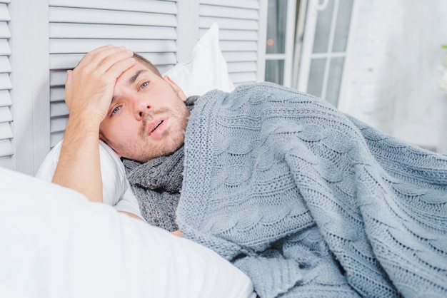 Close-up van een man met koorts zijn voorhoofd met de hand aan te raken