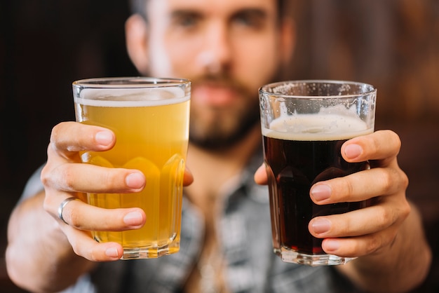 Close-up van een man&#39;s hand met glazen bier en rum