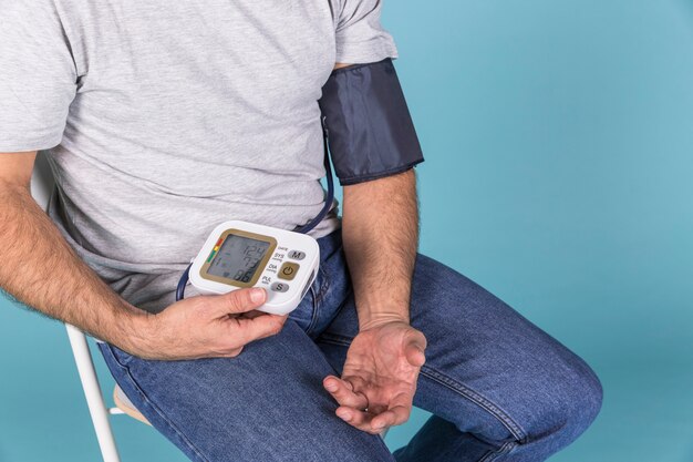 Close-up van een man zittend op een stoel het controleren van de bloeddruk op een elektrische tonometer