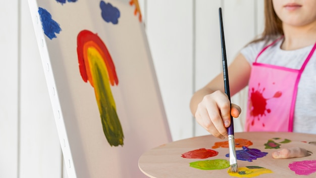 Close-up van een meisje die met verfborstel op canvas schilderen