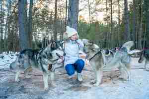 Gratis foto close-up van een meisje met husky's sledehonden in een sneeuw