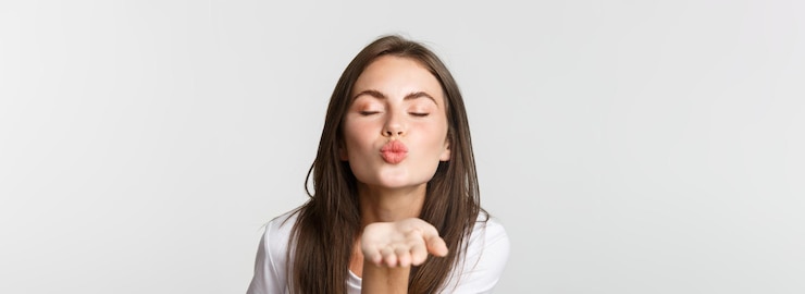 Gratis Foto close-up van een mooi flirterig meisje dat lippen pruilt en een luchtkus naar de camera stuurt