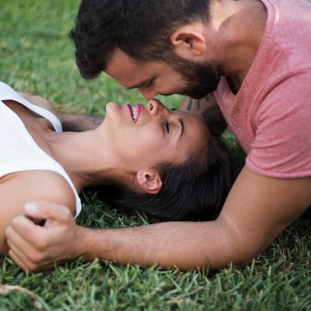 Gratis foto close-up van een mooi romantisch paar dat op gras in park ligt