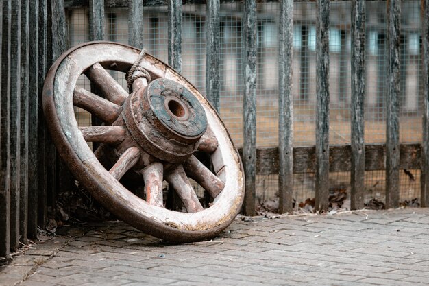 Close-up van een oud houten wiel ter plaatse tegen hekken onder de lichten