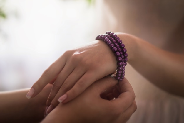 Close-up van een persoon die een paarse armband rond de hand van een vrouw onder de lichten zet