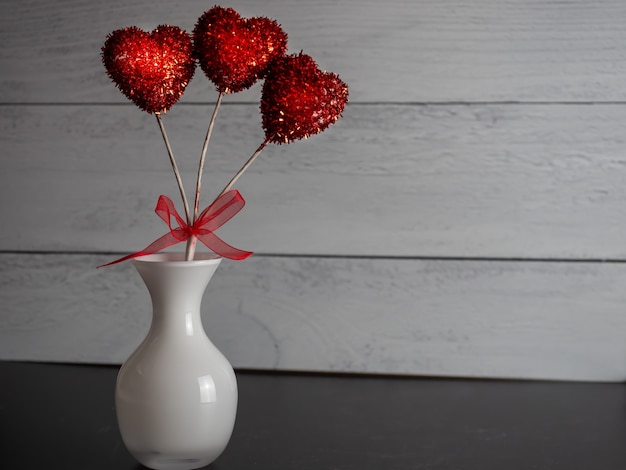 Gratis foto close-up van een rode hartvormige decoratieve pop in een vaas tegen een grijze achtergrond