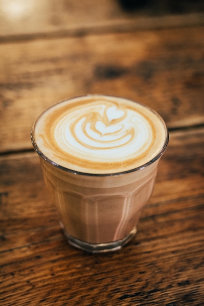 Close-up van een schuimige chocoladedrank in een glas op een houten tafel