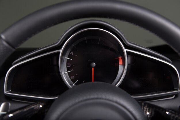 Close-up van een snelheidsmeter en een stuur van een moderne auto onder de lichten