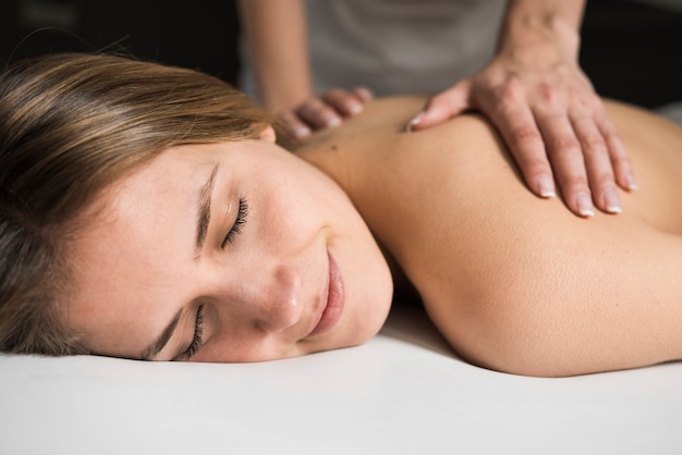 Close-up van een therapeuthand die massage geeft aan mooie jonge vrouw in kuuroord