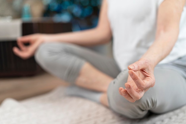 Close-up van een vrouw die asana-positie inneemt Een vrouw ouder dan 50 jaar die thuis yoga doet